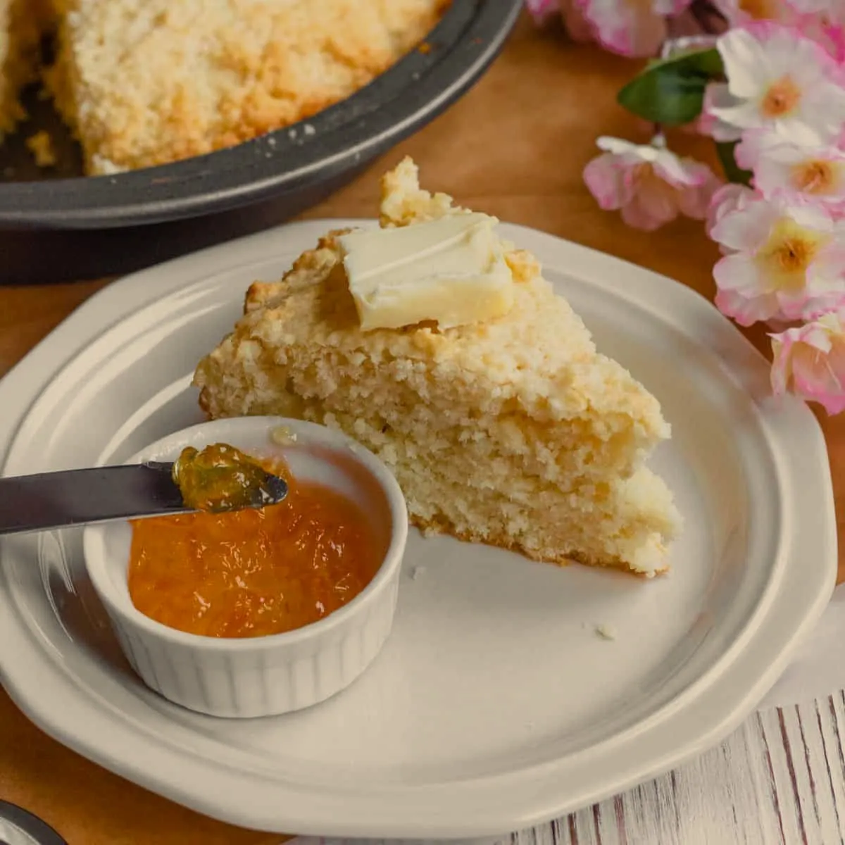 A wedge of johnny cake with butter and guava jam